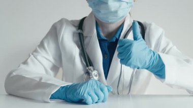 Ameliyat önlüğü ve eldiven giymiş maskeli bir sağlık çalışanı, hasta ve ailelerin sağlık ve sağlıklarına öncelik veren klinik bir ortamda güven, destek ve şefkati temsil eden bir onay veriyor.