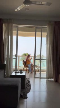 Balkon okyanusu okuma Kafkas kadın kitap ve rahat sandalye, sıcak güneş ışığı, palmiye meltemi, seyahat günlüğü ve düşünceli sabah