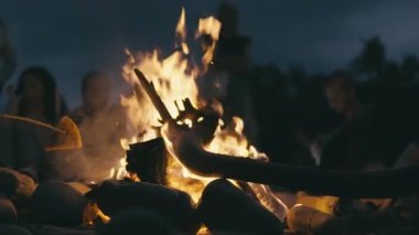Taşlarla ve siluetli figürlerle çevrili parlayan bir kamp ateşi sakin bir akşam manzarası yaratır. Ateş ışığı sıcak bir parıltı yayar, beraberlik ve macera hissi uyandırır.