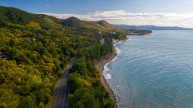 Deniz kıyısındaki tatil köyü, deniz kenarındaki dağ yolu, hava manzarası.
