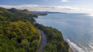 Deniz kıyısındaki tatil köyü, deniz kenarındaki dağ yolu, hava manzarası.