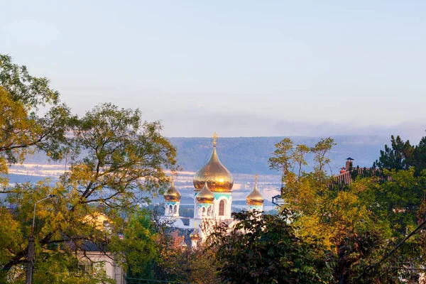 Orthodox cross on dome of church, golden domes of the chrisian church against the backdrop of mountains and blue sky
