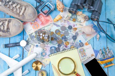 Seyahat konsepti. Gezginlerin aksesuarlarının genel görünümü, temel tatil öğeleri, temel tatil öğeleri: spor ayakkabıları, dürbün, not defteri, saat, telefon, gözlük, şapka, pasaport, para, ton.