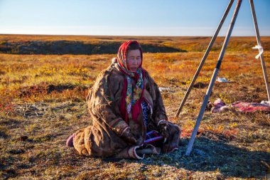 En kuzeyde Yamal, Nenet halkının hayatı ren geyiği çobanı yardımcısı, yerde oturmuş bekleyen kadın.