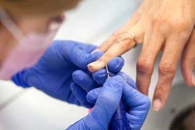 Profesyonel manikür. Manikür salonundaki bir kadının yakın çekimi. Elektrikli ojeli profesyonel oje, seçici odaklı.