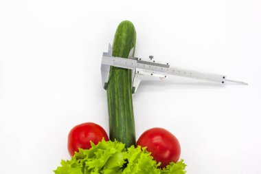 Male problems, Concept - the size of a male penis, Concept of increasing male penis and operation, increase male organ, cucumber and tomatoes with calipers on a white background.