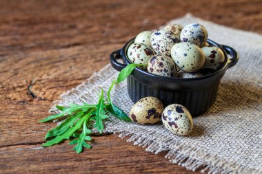 Bıldırcın yumurtalı kase, ev yapımı peçetedeki yumurtalar, eski, karanlık ahşap arka plan..