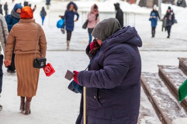 Zavallı yaşlı kadın sadaka istiyor, aç evsiz dilenci kadın 15 Şubat 2021 'de Moskova, Rusya' dan geçen insanlardan şehrin sokaklarında para dileniyor..