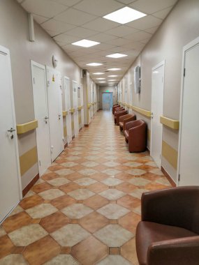 Hastane koridoru, hastanede uzun bir koridor, kapılar ve yansımalar var.