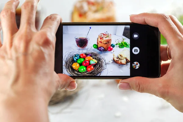 Easter cake Kraffin (Cruffin), with nuts and candied fruit sprinkled with powdered sugar, 2021 trend of the easter cake. Top view, female hands take off Easter cake on smartphone.