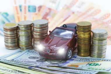 Araba sigortası kavramı. Otomobil ya da araba sigortası uygulaması. Araba modeli, dolar banknotları ve madeni paraların arka planına karşılık anahtarlar.
