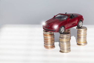 Araba sigortası kavramı. Otomobil ya da araba sigortası uygulaması. Araba modelinin arka planında dolar banknotları ve bozuk paralar var. Seçici odak noktası..