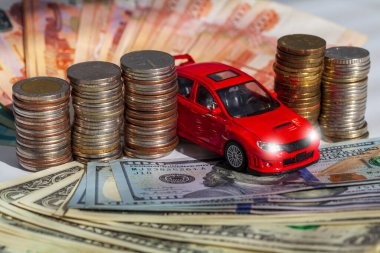 Araba sigortası kavramı. Otomobil ya da araba sigortası uygulaması. Araba modelinin arka planında dolar banknotları ve bozuk paralar var. Seçici odak noktası..