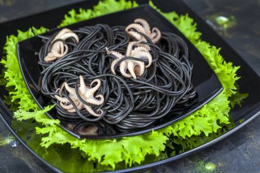 Siyah spagetti. Siyah arka planda ahtapot olan siyah deniz ürünleri makarnası. Akdeniz gurme yemekleri. Yakın çekim görünümü