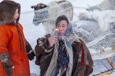 Tundra 'nın bir sakini, Kuzey' in yerli sakinleri, elinde maytap tutan bir kız, hayatında ilk kez bir maytap tutan kadın, kızıyla şaşkınlıkla bakıyor.
