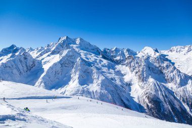 Kafkasya Dağları, Belalakaya, Sofrudzhu ve Sulakhat dağları ile kayak yamacının panoramik manzarası kış günü ufukta. Dombai kayak merkezi, Batı Kafkasya, Karachai-Cthe, Rusya.