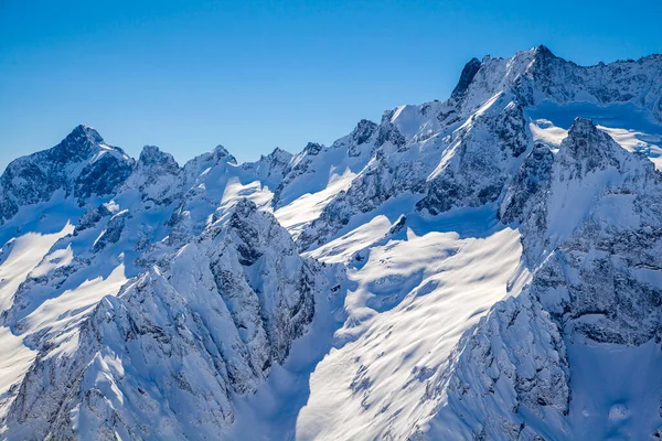 Kafkasya Dağları, Belalakaya, Sofrudzhu ve Sulakhat dağları ile kayak yamacının panoramik manzarası kış günü ufukta. Dombai kayak merkezi, Batı Kafkasya, Karachai-Cthe, Rusya.