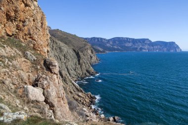 Kırım 'daki Karadeniz kıyısı, Sivastopol' daki Cape Fiolent manzarası. Panoramik deniz manzarası, sakin gök mavisi deniz, bulutlar ve parlak gökyüzü..