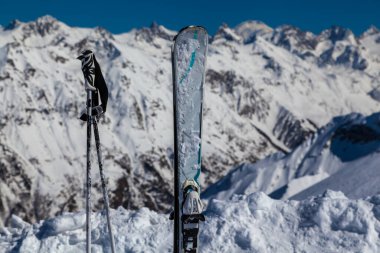 Kayak ve kayak direkleri kayak pistinin arka planında dikey olarak dururlar. Dombai Kayak Merkezi
