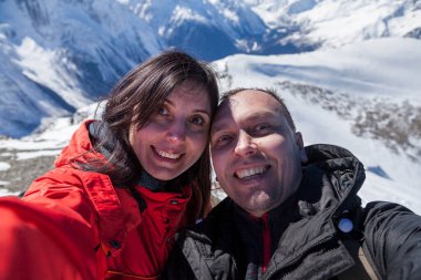 Dağlarda selfie çeken mutlu genç bir çift. Mutlu çift, dağlarda selfie çekerken kameraya gülümseyen başarılı yürüyüşçüler.