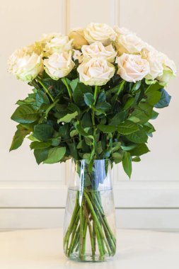 Vazoda büyük bir buket beyaz gül bej arka planda, dikey foto