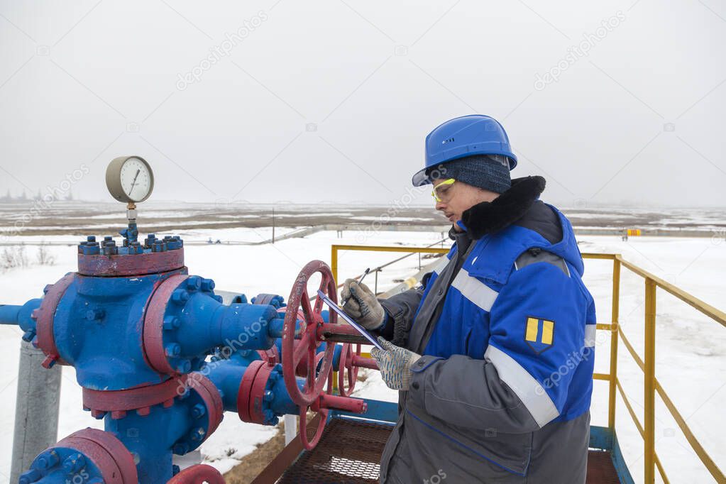 Oil, gas industry. The mechanic - the repairman, gas production operator opens the valve, gas equipment and fitting at the well, the operator changes the pressure gauge on the well