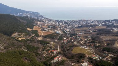 Kırım 'daki Yalta Körfezi' nin güzel hava manzarası. İnsansız hava aracından Yalta seti, rıhtımdaki eski deniz feneri, deniz manzarası ve dağlardaki şehir binaları, Kırım.