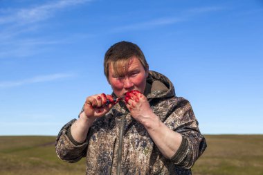 The extreme north, Yamal, the preparation of deer meat, the male reindeer breeder eats fresh meat, venison clipart