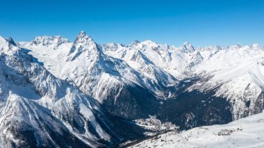 Kafkasya Dağları, Belalakaya, Sofrudzhu ve Sulakhat dağları ile kayak yamacının panoramik manzarası kış günü ufukta. Dombai kayak merkezi, Batı Kafkasya, Karachai-Cthe, Rusya.
