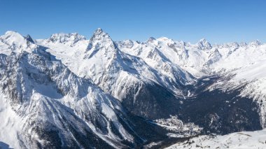 Kafkasya Dağları, Belalakaya, Sofrudzhu ve Sulakhat dağları ile kayak yamacının panoramik manzarası kış günü ufukta. Dombai kayak merkezi, Batı Kafkasya, Karachai-Cthe, Rusya.