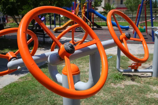 Симуляторы ярко-оранжевых металлических рулевых колес на детской площадке Лицензионные Стоковые Изображения