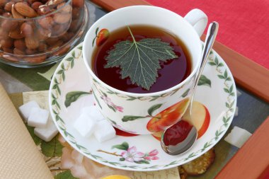 Freshly brewed black tea with currant leaf in a porcelain dish clipart