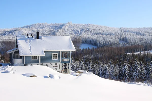 Бревенчатый дом в снегу под солнцем Лицензионные Стоковые Изображения