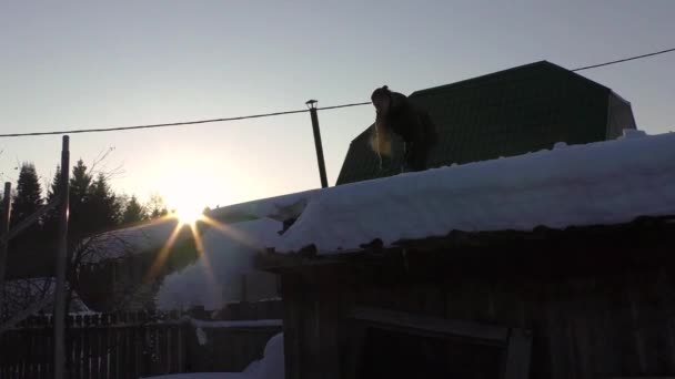 Jovem cara bate a neve do telhado — Vídeo de Stock