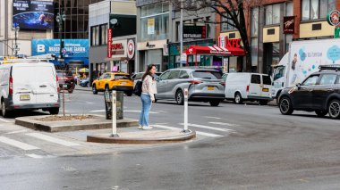 Manhattan, New York, ABD - 16 Şubat 2023: Gri bir kış gününde şehir merkezindeki caddeden geçen kadın