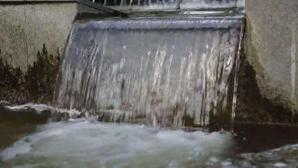 Stikaet de agua abajo. Una pequeña cascada en una fuente . — Vídeos de Stock