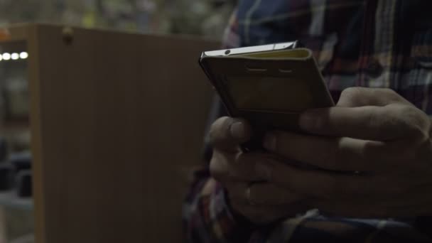 Muž v rukou telefonu. Chlapa, který sedí na židli drží smartphone — Stock video