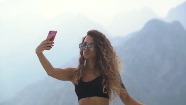 Femme aux longs cheveux bouclés fait selfie contre les montagnes — Video