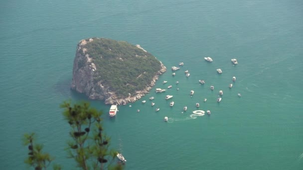 Морской лайнер и небольшие корабли возле скалистого острова на лазурном море — стоковое видео