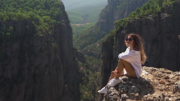 Donna in camicia bianca e sneakers su roccia contro le montagne — Video Stock