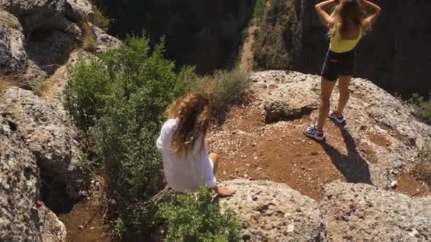 Las mujeres están de pie en piedra cerca de pista delgada en la cresta a las montañas — Vídeos de Stock