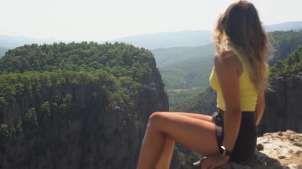 Woman sits on stone top looking at picturesque mountains — Stock Video