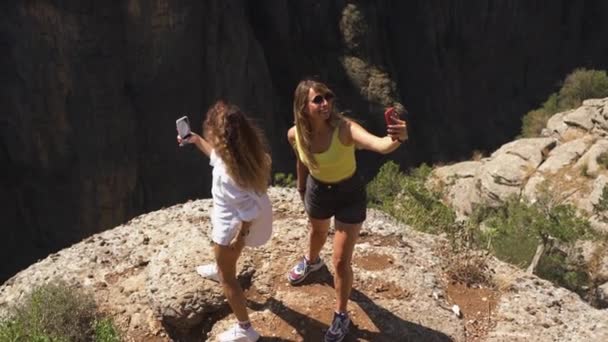 Radosne kobiety stoją na skale robiąc selfie w pobliżu dużej dziury — Wideo stockowe