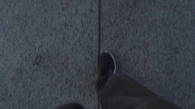 Spor ayakkabılı gri pantolonlu kişi yol boyunca yürür.