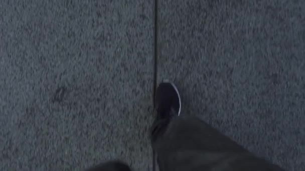Людина в сірих спортивних штанах з кросівками йде по дорозі — стокове відео