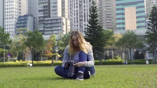 Žena se dívá na obrázky na digitálním fotoaparátu na zeleném poli — Stock video
