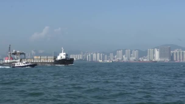 Navio de carga e barco a motor navegam ao longo do oceano azul passando pela cidade — Vídeo de Stock