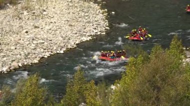Turistler fırtınalı nehir boyunca kürek çekerek taşlı kıyıları geçiyor