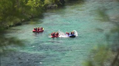 Turistler, dağ nehri boyunca yelkenli teknelerle su sıçratıyor