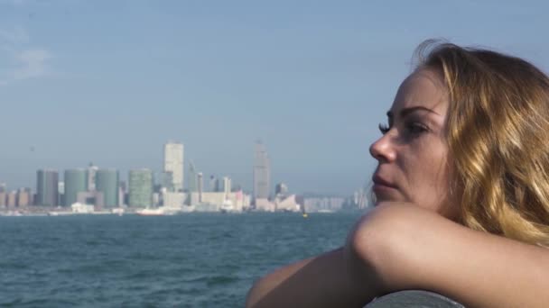 Блондинка опирается на перила возле удивительного лазурного океана — стоковое видео
